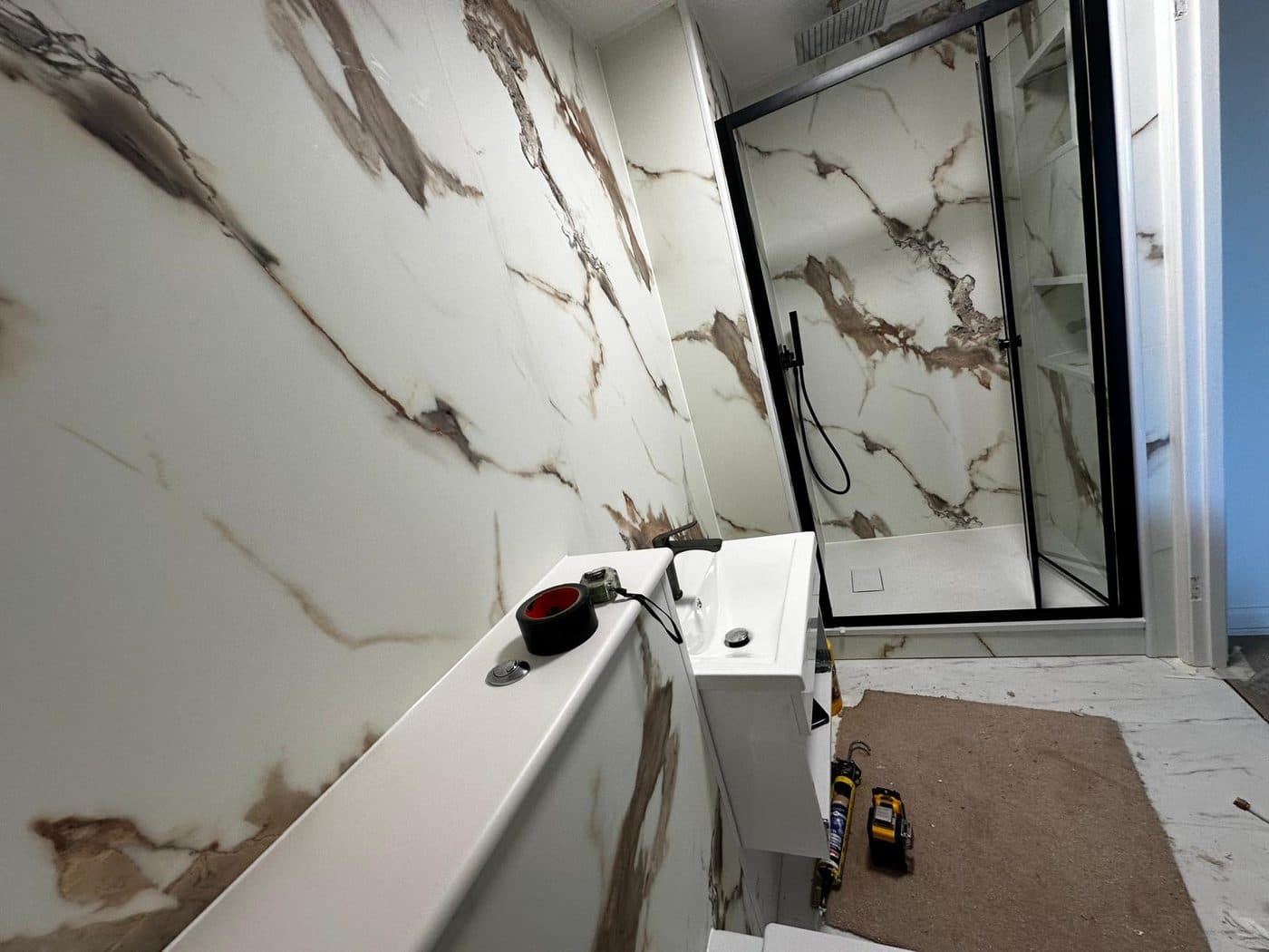 Luxury London bathroom renovation with blue onyx-effect porcelain walls and brushed gold shower fittings by ERCO Home Improvements