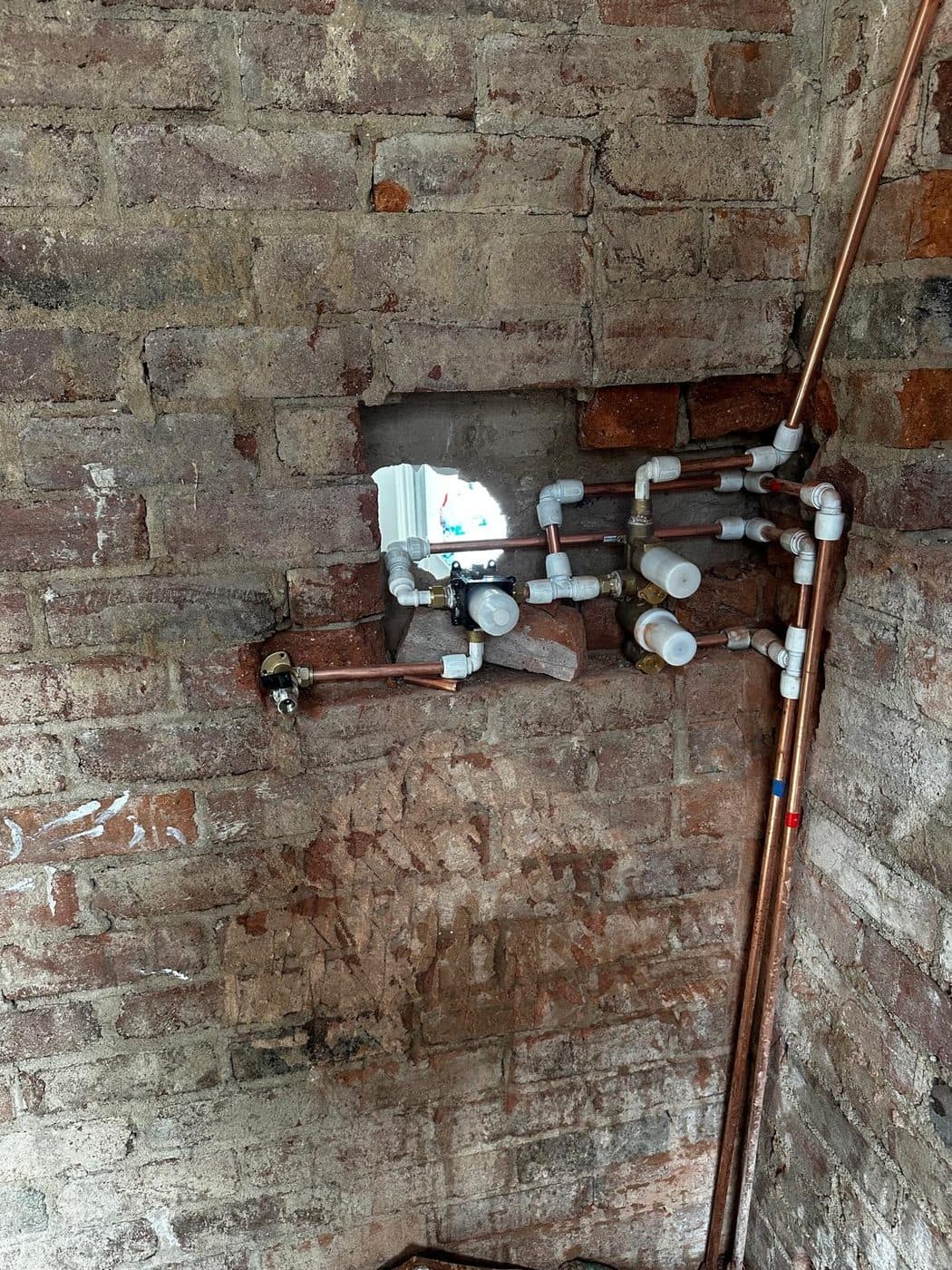Neat copper pipework first-fix plumbing on exposed brick for a bathroom renovation by ERCO Home Improvements London