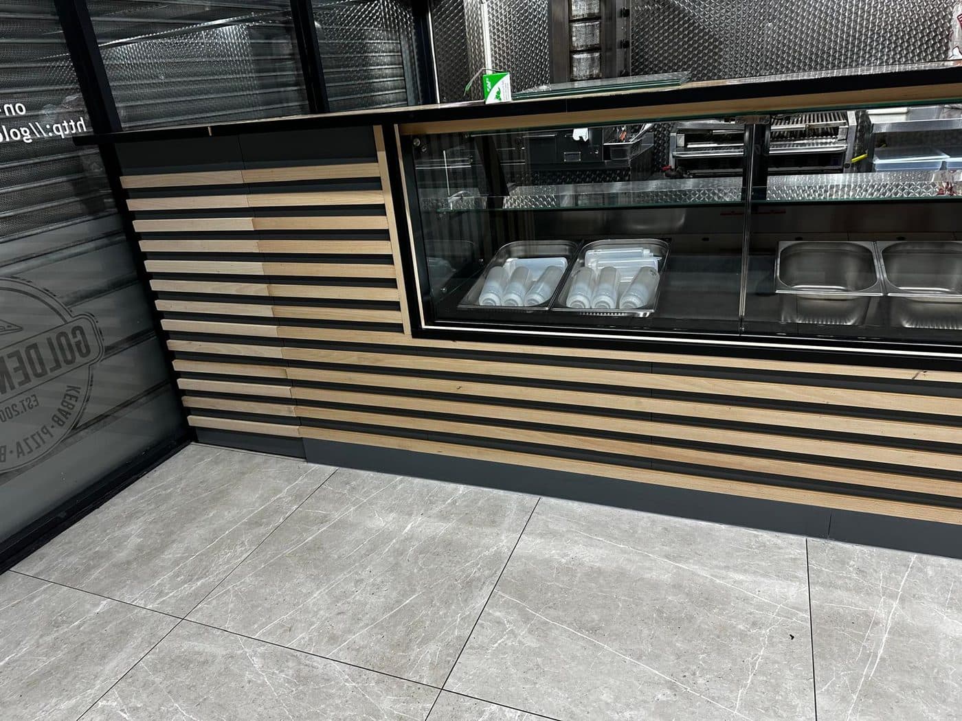 Bespoke takeaway shop counter with timber slat cladding and stainless display fitted by ERCO Home Improvements London